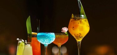 a set of different alcoholic cocktails in glass glasses on the bar counter